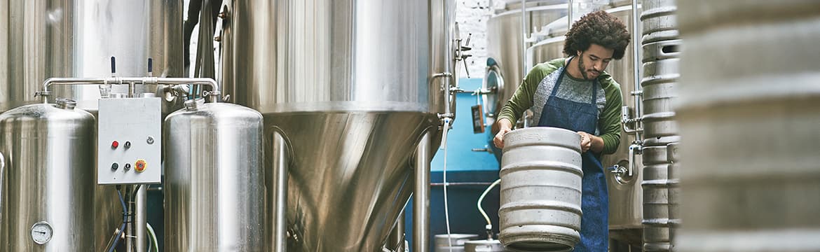 Photo of a brewery worker moving kegs