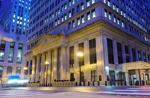 The Chicago Fed building from the front, lit warmly by streetlights in the early morning.