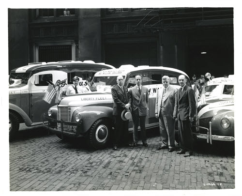 Several men, including Clifford Young, pose with the bank's Liberty Loan Fleet of cars.