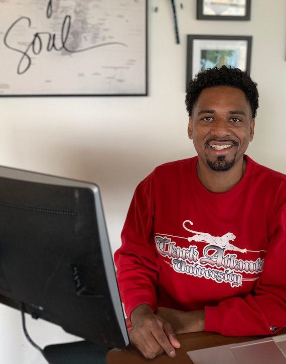A smiling photo of Dante Haygood, a participant in the Bank's internship program, seated at his desk.
