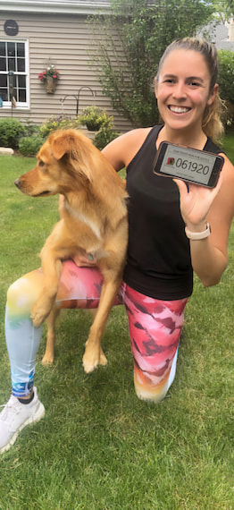 A woman in running clothes poses with her dog before participating in the Juneteenth Run for Justice virtual 5k event.