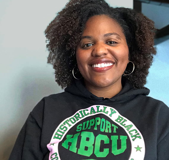 A smiling photo of employee Kristin Hamb. She is wearing an HBCU sweatshirt.