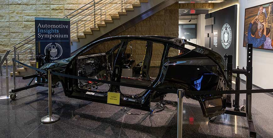 A photograph depicts the assembled frame of a Tesla vehicle on display in the lobby of the Federal Reserve Bank of Chicago’s Detroit branch.